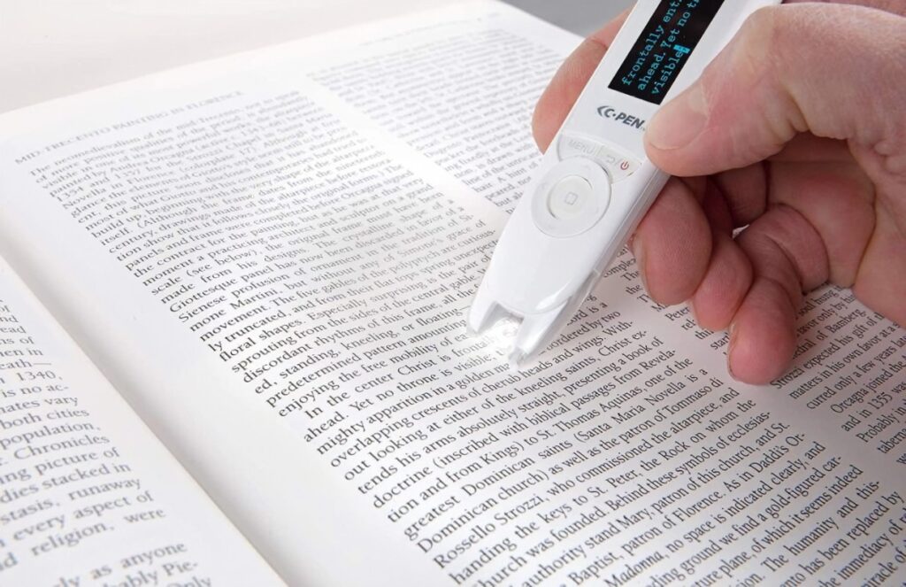 Image of a hand holding a pen reading device against a page of text.