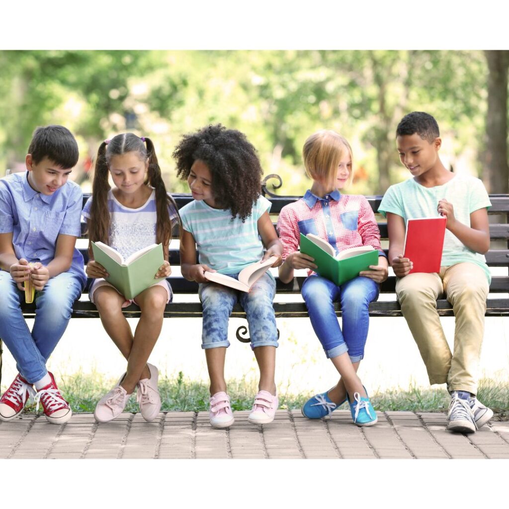 A group of children sitting outside reading books.